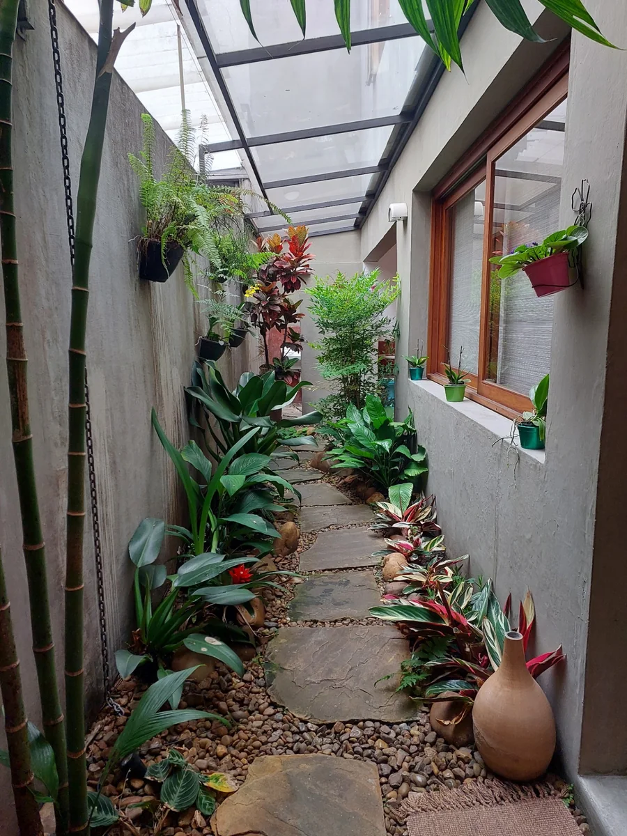 Corredor com jardim interno e caminho de pedras na clínica.