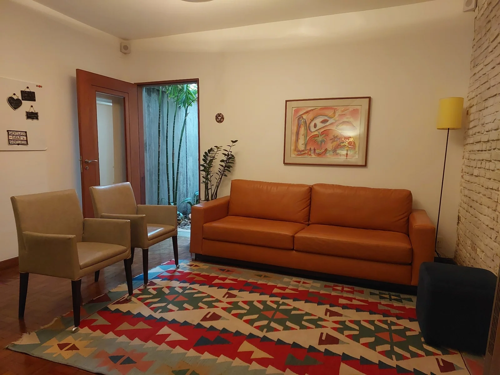 Sala de espera acolhedora da clínica com sofá e poltronas.
